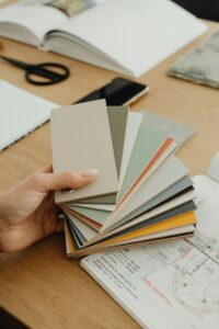 Hand holding color swatches over blueprints and open book